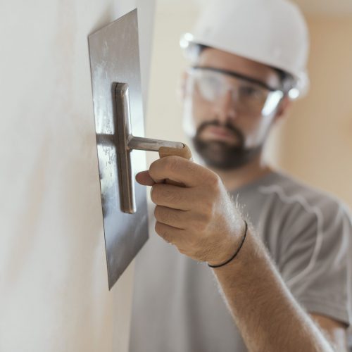 Professional craftsman applying plaster with a trowel, home renovation concept